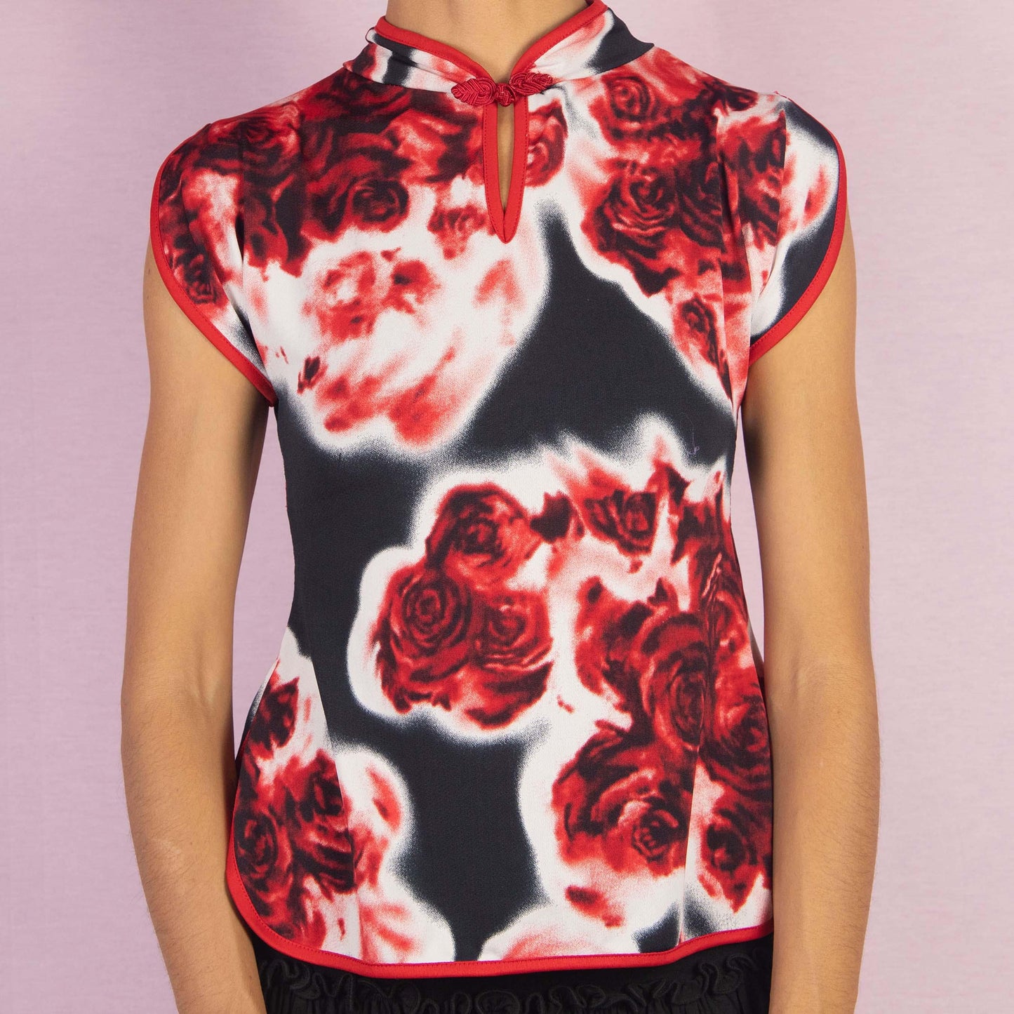 The Vintage 90s Rose Print Top is a striking piece featuring a bold red and black rose print and cap sleeves. The design is enhanced by a Qipao-inspired high collar with a decorative frog closure and a keyhole detail.