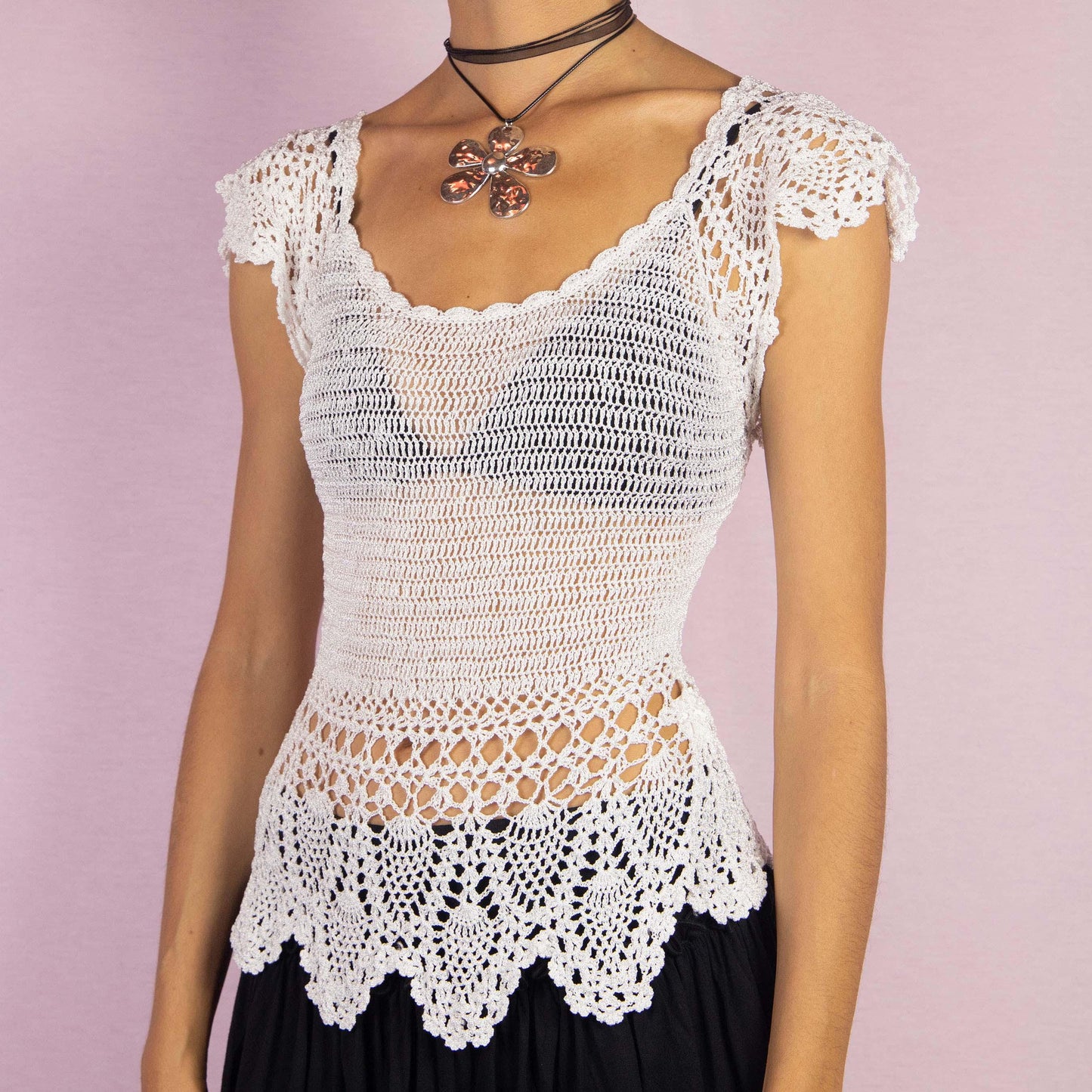 The Y2K White Crochet Top is a vintage 2000s sleeveless top featuring intricate crochet detailing and a delicate scalloped hemline. Its semi-sheer design and fitted silhouette make it a perfect for a breezy summer look.