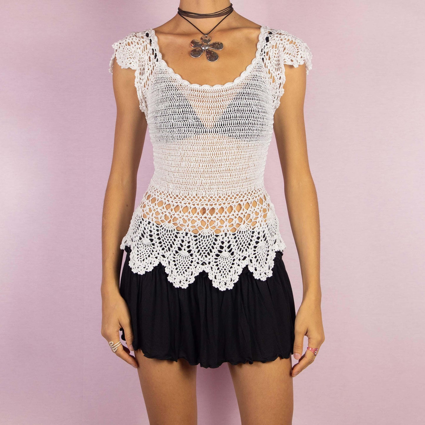 The Y2K White Crochet Top is a vintage 2000s sleeveless top featuring intricate crochet detailing and a delicate scalloped hemline. Its semi-sheer design and fitted silhouette make it a perfect for a breezy summer look.