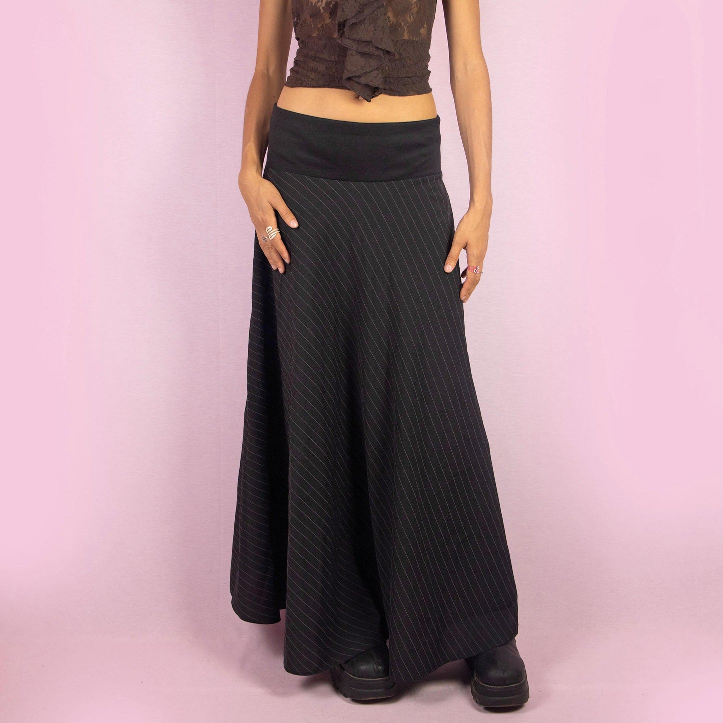 The Y2K Black Pinstripe Maxi Skirt is a vintage 2000s statement piece featuring a flowing silhouette with pinstripes for a sophisticated touch and a wide elastic waistband. Perfect for both office wear and casual outings.