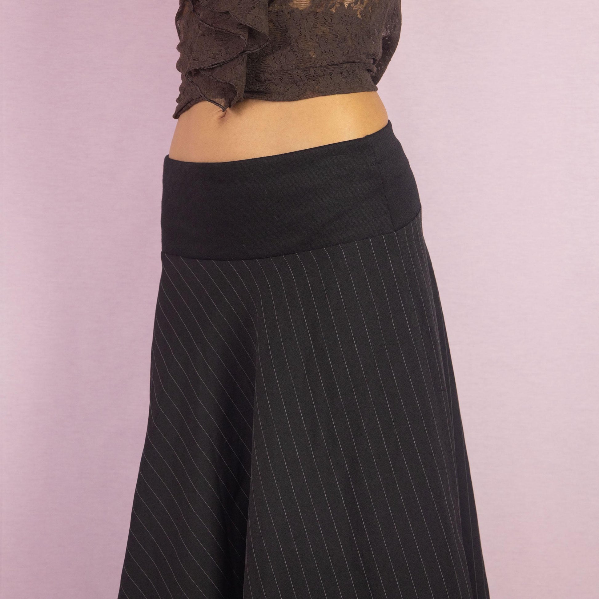 The Y2K Black Pinstripe Maxi Skirt is a vintage 2000s statement piece featuring a flowing silhouette with pinstripes for a sophisticated touch and a wide elastic waistband. Perfect for both office wear and casual outings.