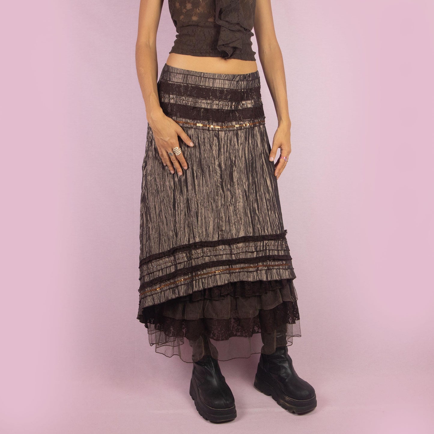 The Y2K Brown Layered Midi Skirt is a vintage 2000s piece featuring an earthy brown palette with a mix of crinkled fabric, lace, and mesh layers. The mid-waisted design and asymmetrical hemline create a flowy, bohemian silhouette, with a side zipper