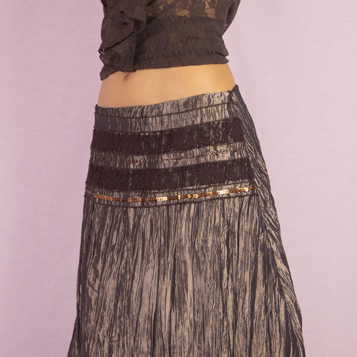 The Y2K Brown Layered Midi Skirt is a vintage 2000s piece featuring an earthy brown palette with a mix of crinkled fabric, lace, and mesh layers. The mid-waisted design and asymmetrical hemline create a flowy, bohemian silhouette, with a side zipper