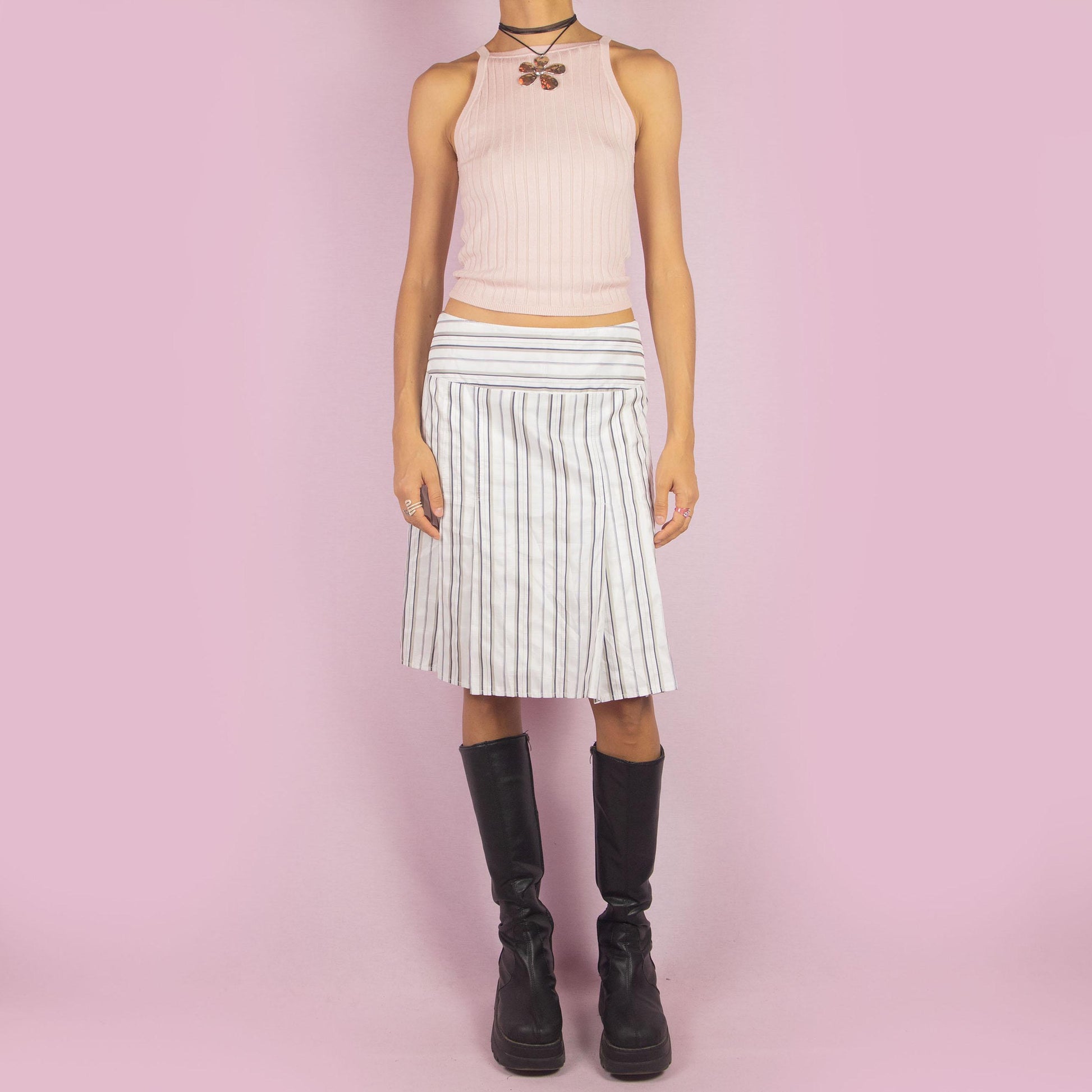 The Vintage 90s White Pinstripe Pleated Skirt features a classic pinstripe pattern with a flared silhouette, a mid-waist fit and a back zipper closure. Perfect for both office wear and casual outings.