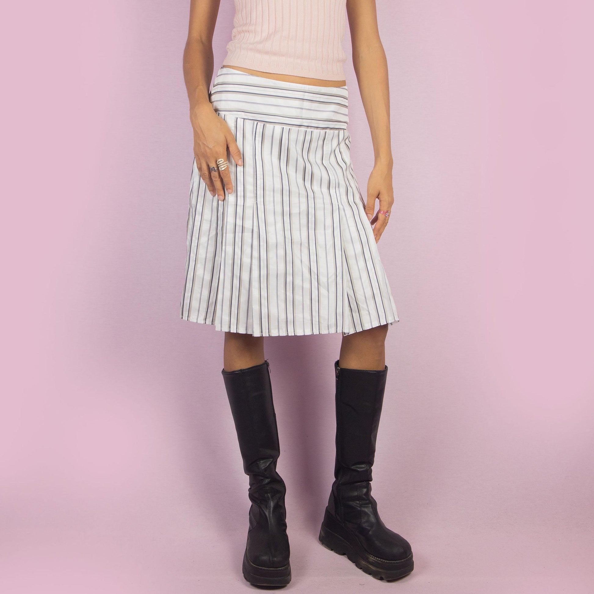 The Vintage 90s White Pinstripe Pleated Skirt features a classic pinstripe pattern with a flared silhouette, a mid-waist fit and a back zipper closure. Perfect for both office wear and casual outings.