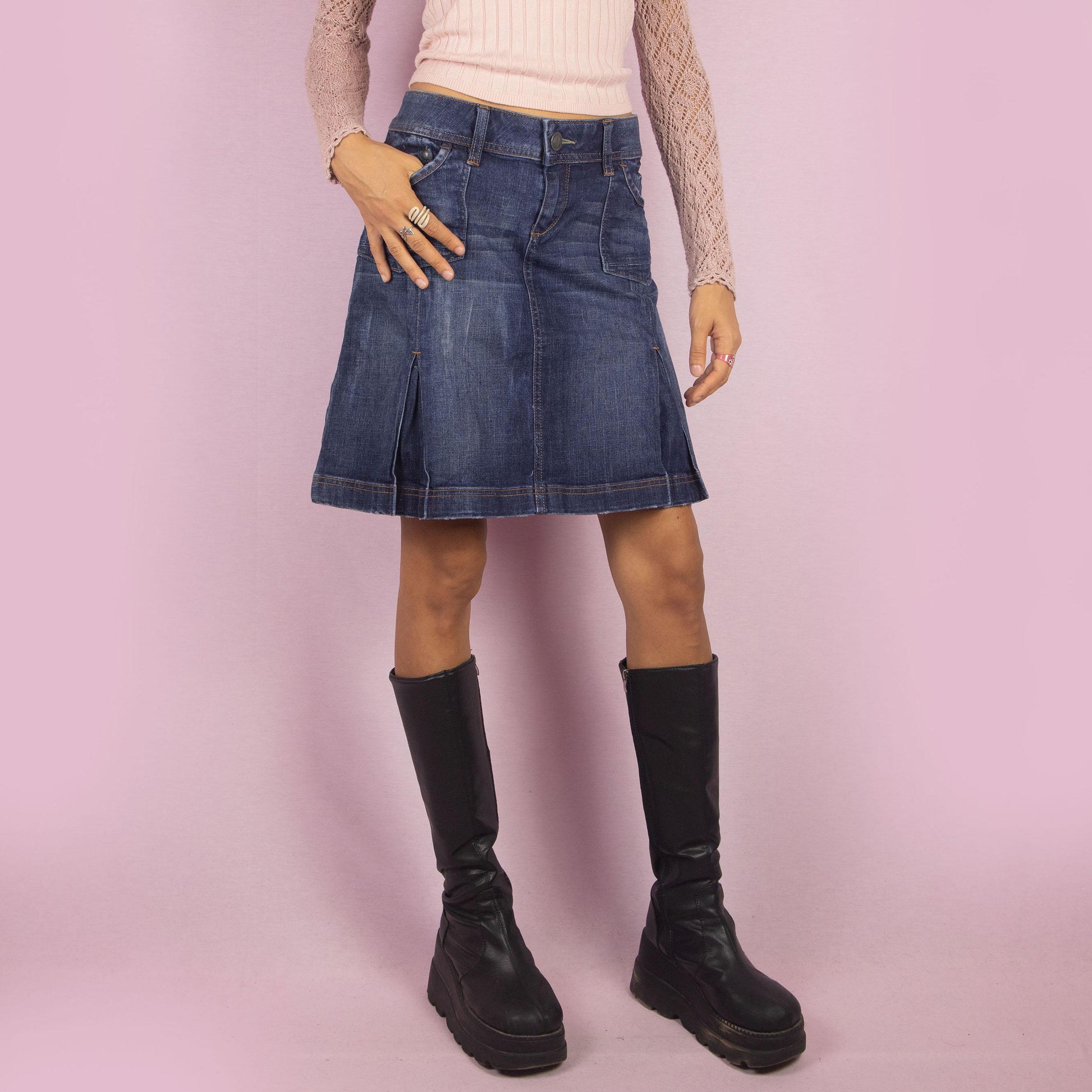 The Y2K Denim Pleated Skirt is a vintage 2000s piece featuring a structured A-line design with stitched pleats, pockets, a button-and-zipper front closure and stretchy fabric. Ideal for casual and chic everyday outfits.