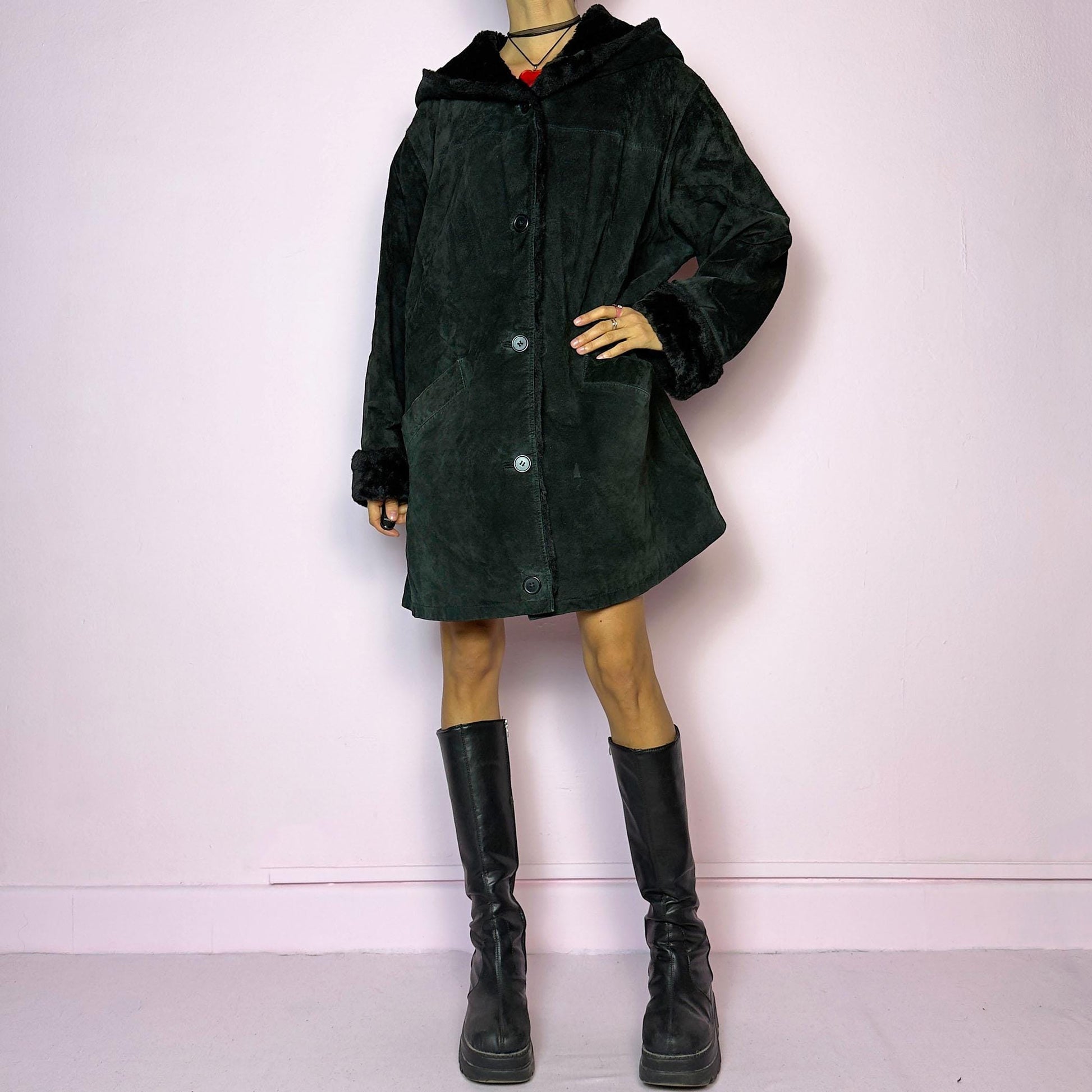 The Vintage 90s Black Hooded Leather Coat features a sleek design crafted from black leather with a cozy hood and a button-front closure. Accentuated with faux fur cuffs and pockets, this warm winter coat is ideal for casual chilly days.