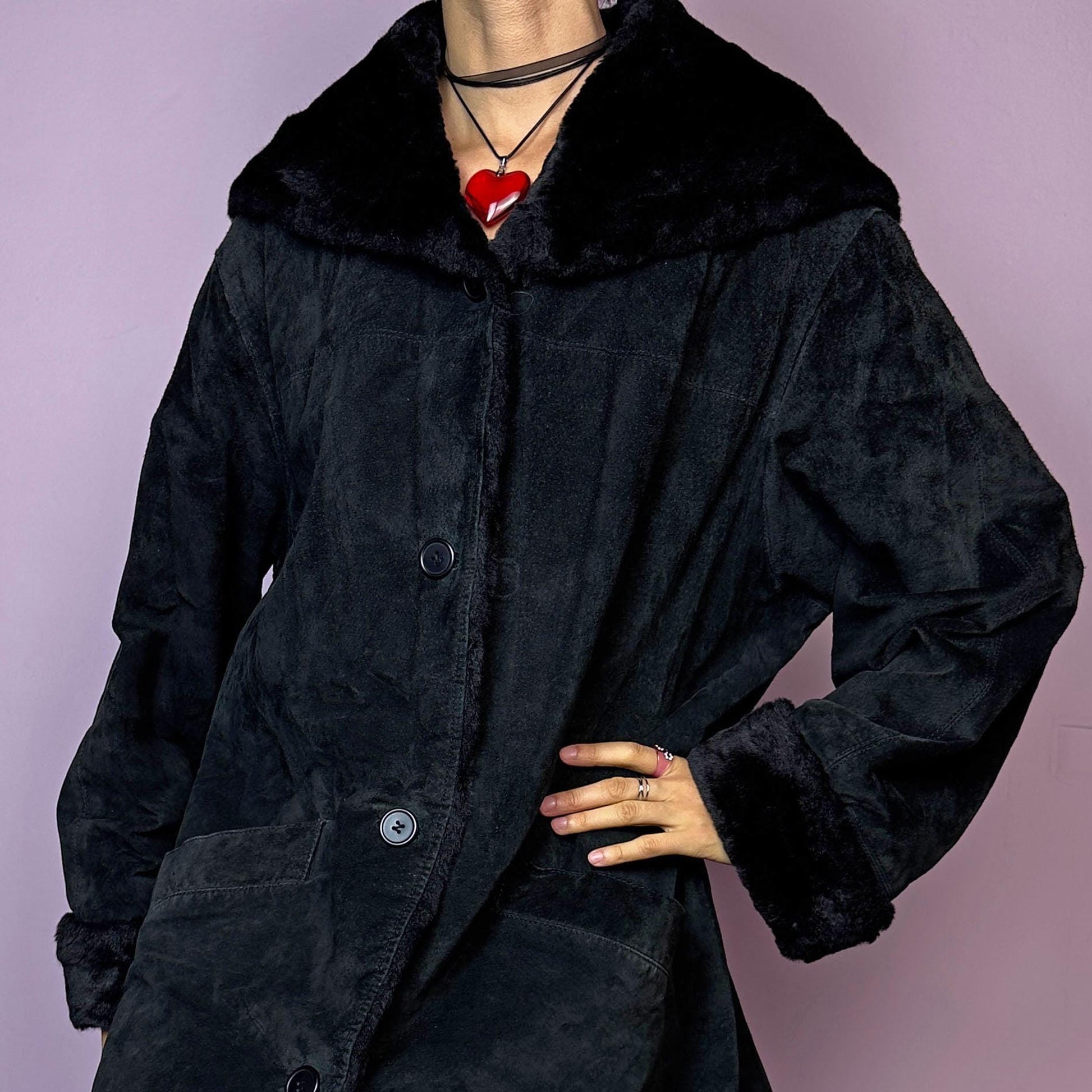 The Vintage 90s Black Hooded Leather Coat features a sleek design crafted from black leather with a cozy hood and a button-front closure. Accentuated with faux fur cuffs and pockets, this warm winter coat is ideal for casual chilly days.