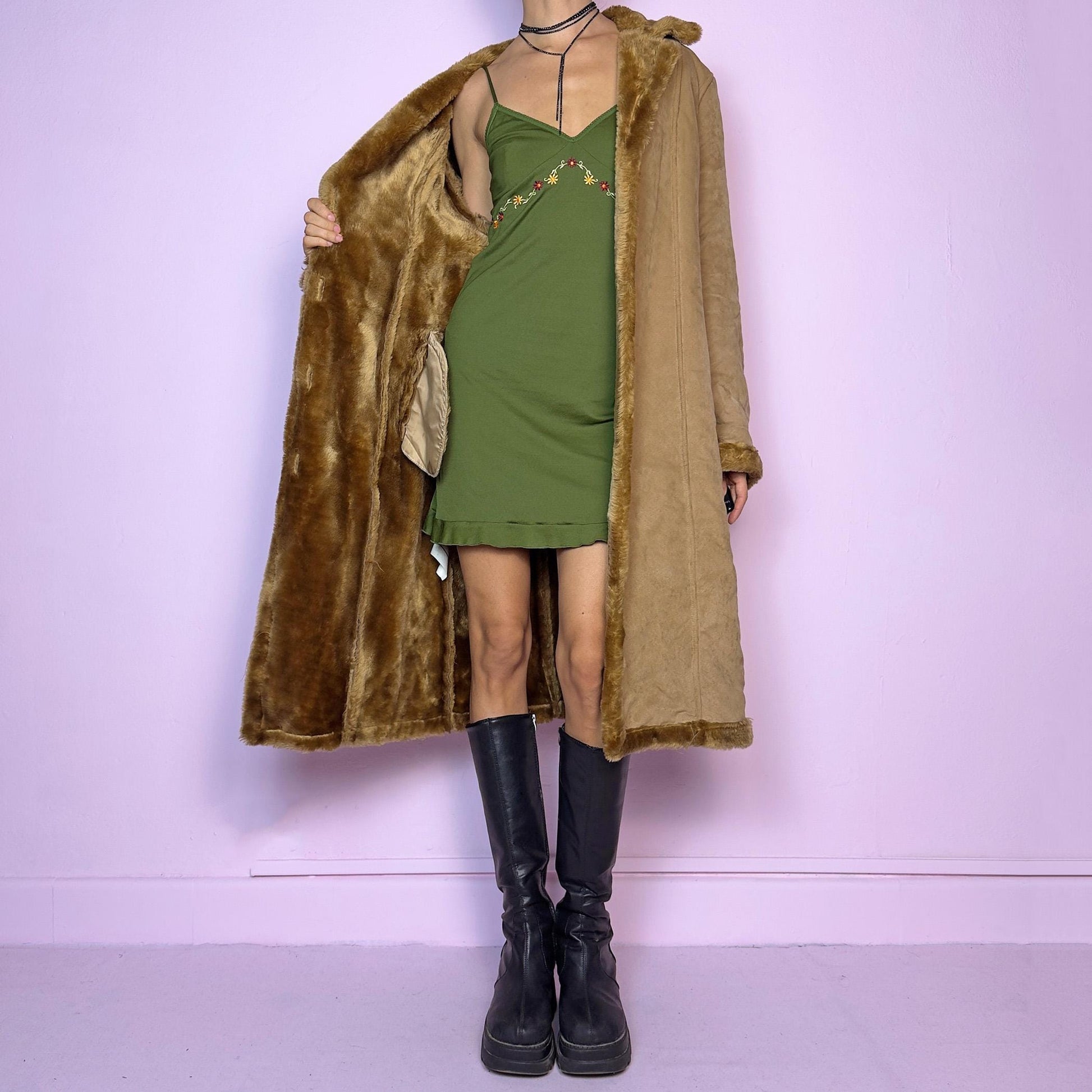 The Y2K Faux Suede Maxi Coat is a vintage 2000s cozy piece featuring a classic camel-tone faux suede exterior accented with plush faux fur trim along the collar, cuffs, and hem. This longline coat includes button-front closures and a tailored fit