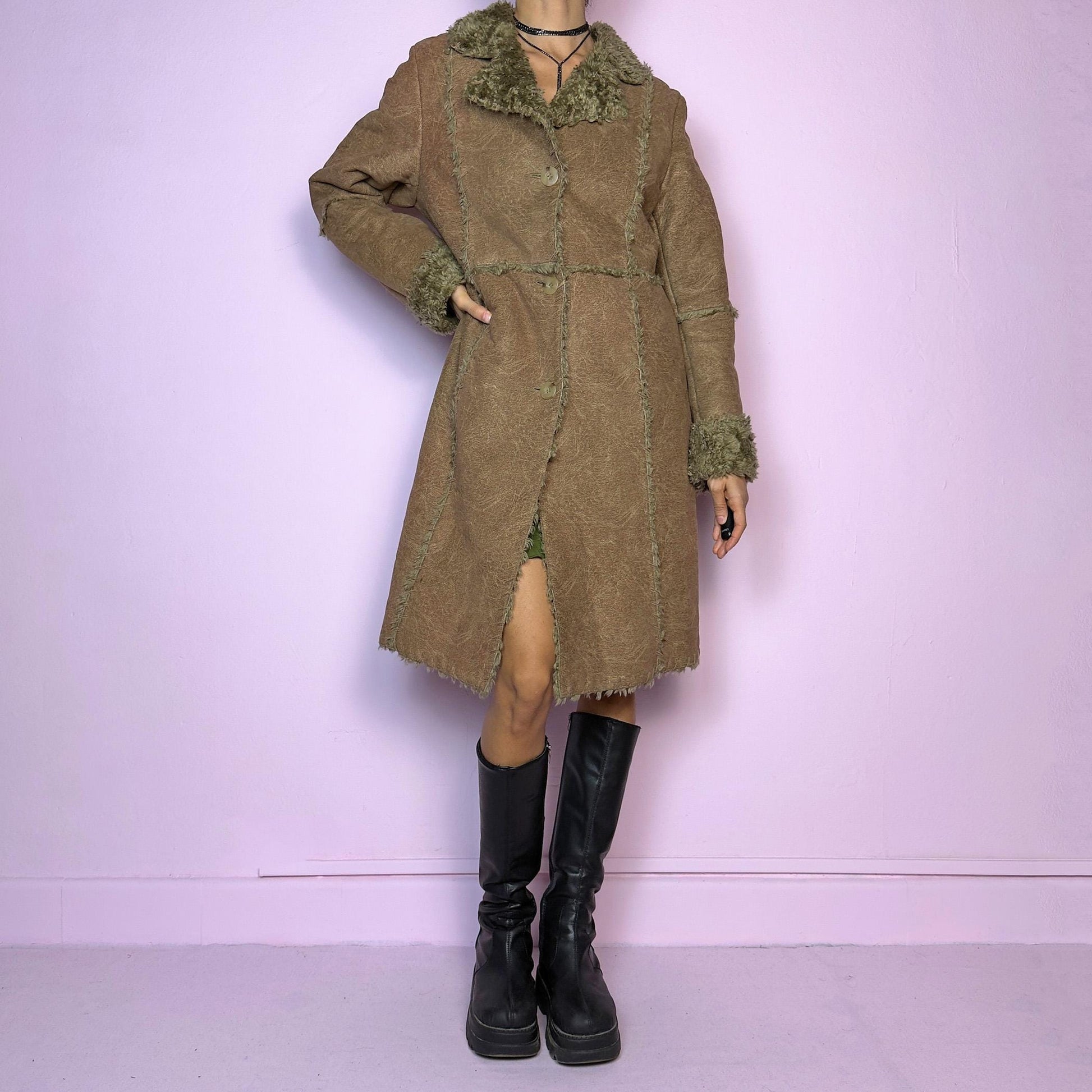 The Y2K Faux Fur Suede Long Coat is a vintage 2000s cozy piece featuring a soft brown faux suede exterior and faux shearling trim along the collar, cuffs, and seams. Its structured silhouette features button-front closure and pockets