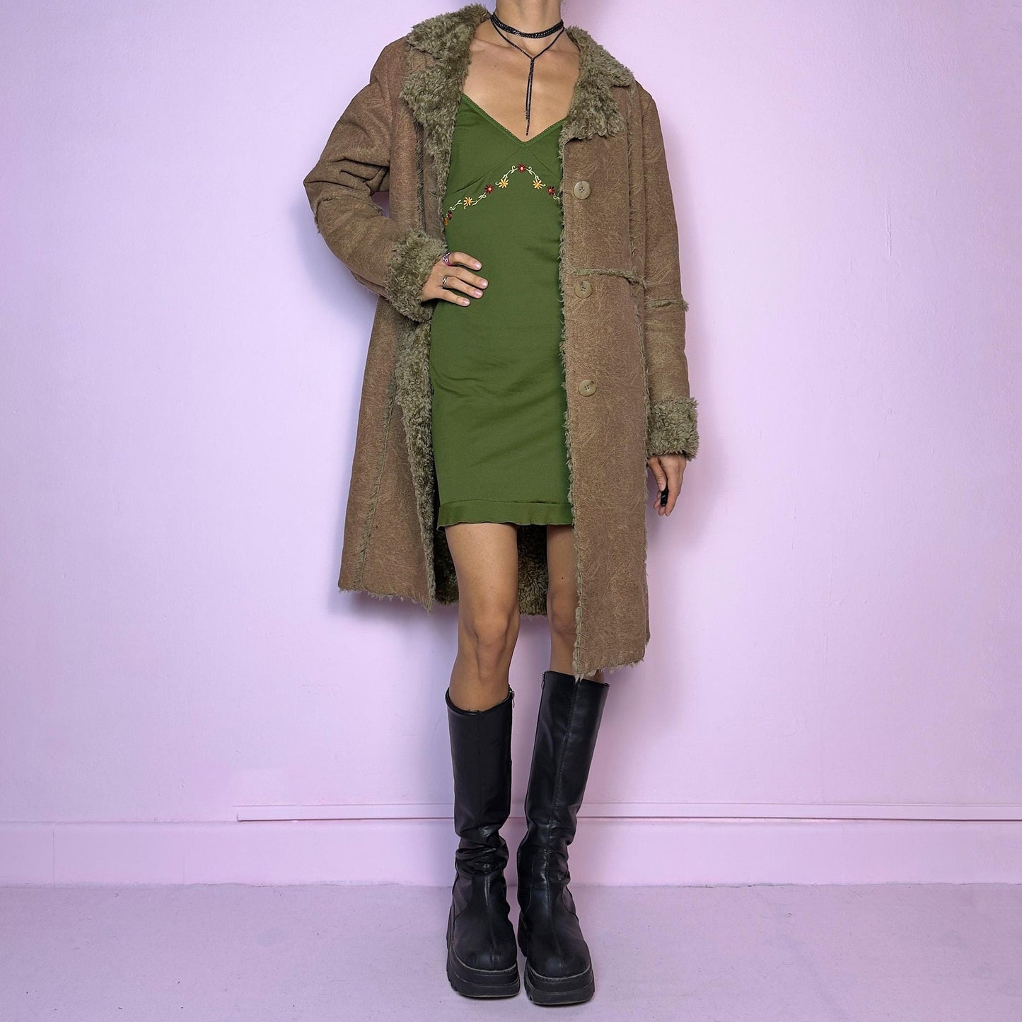 The Y2K Faux Fur Suede Long Coat is a vintage 2000s cozy piece featuring a soft brown faux suede exterior and faux shearling trim along the collar, cuffs, and seams. Its structured silhouette features button-front closure and pockets