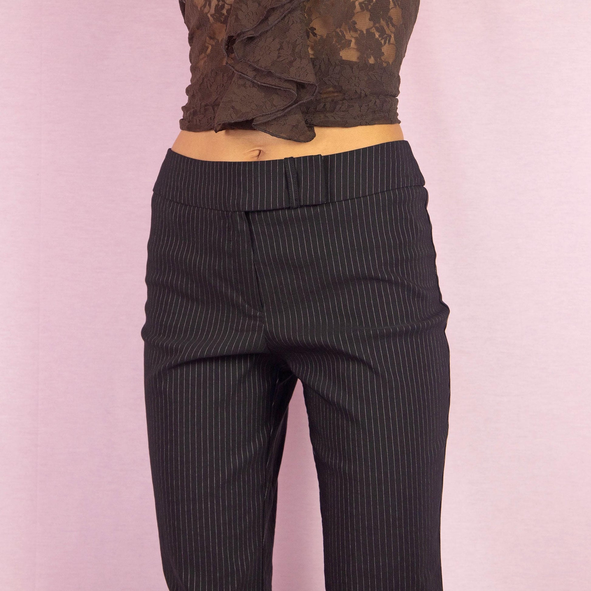 The Y2K Black Pinstripe Straight Pants are a vintage 2000s classic featuring a tailored straight-leg design with subtle pinstripes. Made from a stretchy fabric, they are perfect for office wear or chic casual outfits.