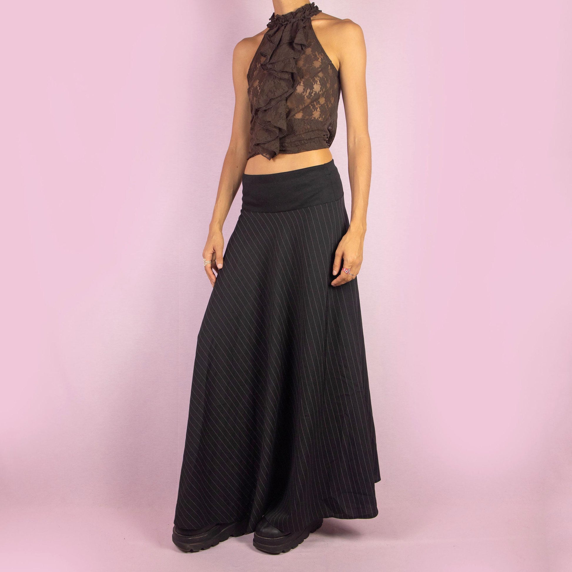 The Y2K Black Pinstripe Maxi Skirt is a vintage 2000s statement piece featuring a flowing silhouette with pinstripes for a sophisticated touch and a wide elastic waistband. Perfect for both office wear and casual outings.