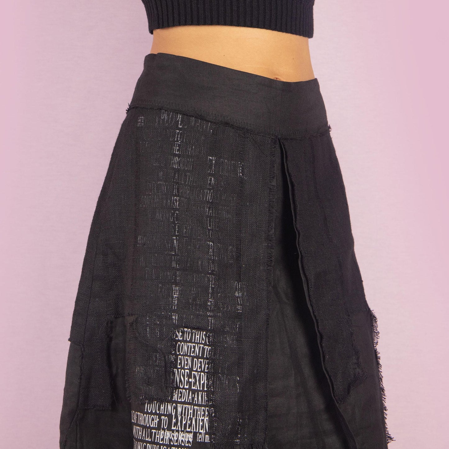 The Y2K Layered Black Midi Skirt features a unique design with contrasting text panels and raw hem details for an edgy and contemporary look. Its structured fit, midi length, low-rise waist, and back zipper closure make it perfect for casual looks.