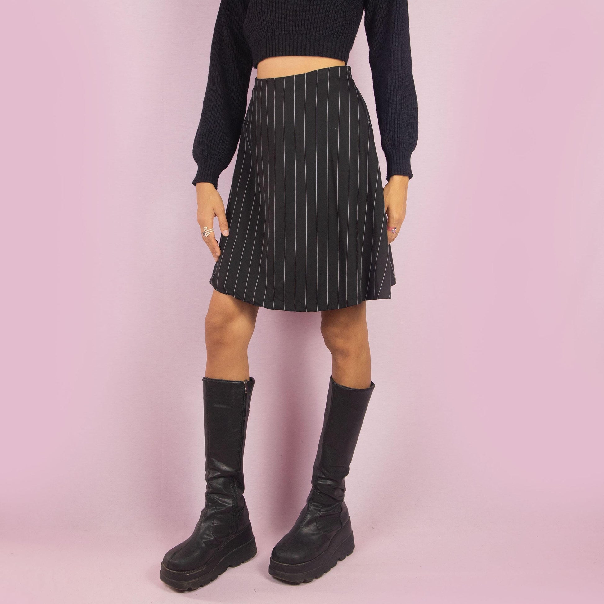 The Y2K Black Pinstripe Mini Skirt is a vintage 2000s piece featuring a chic pinstripe pattern, a flattering A-line silhouette, and a mini length. It also includes a side zipper closure. Perfect for both office looks and casual outings.