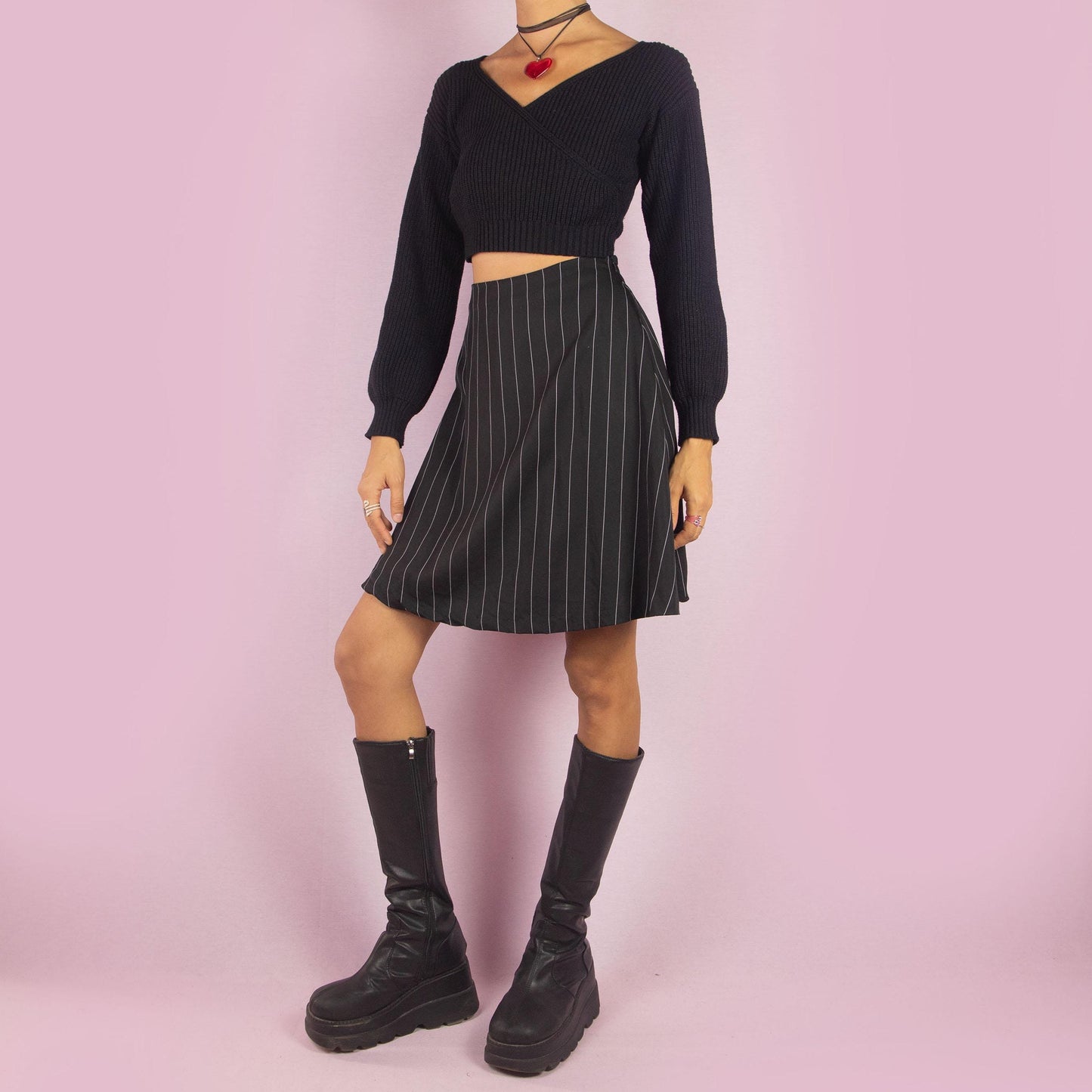 The Y2K Black Pinstripe Mini Skirt is a vintage 2000s piece featuring a chic pinstripe pattern, a flattering A-line silhouette, and a mini length. It also includes a side zipper closure. Perfect for both office looks and casual outings.