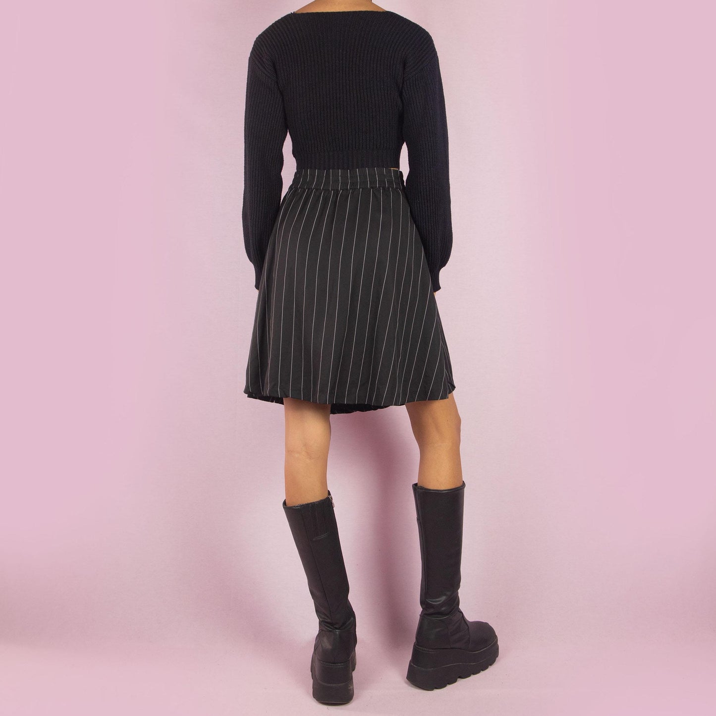 The Y2K Black Pinstripe Mini Skirt is a vintage 2000s piece featuring a chic pinstripe pattern, a flattering A-line silhouette, and a mini length. It also includes a side zipper closure. Perfect for both office looks and casual outings.