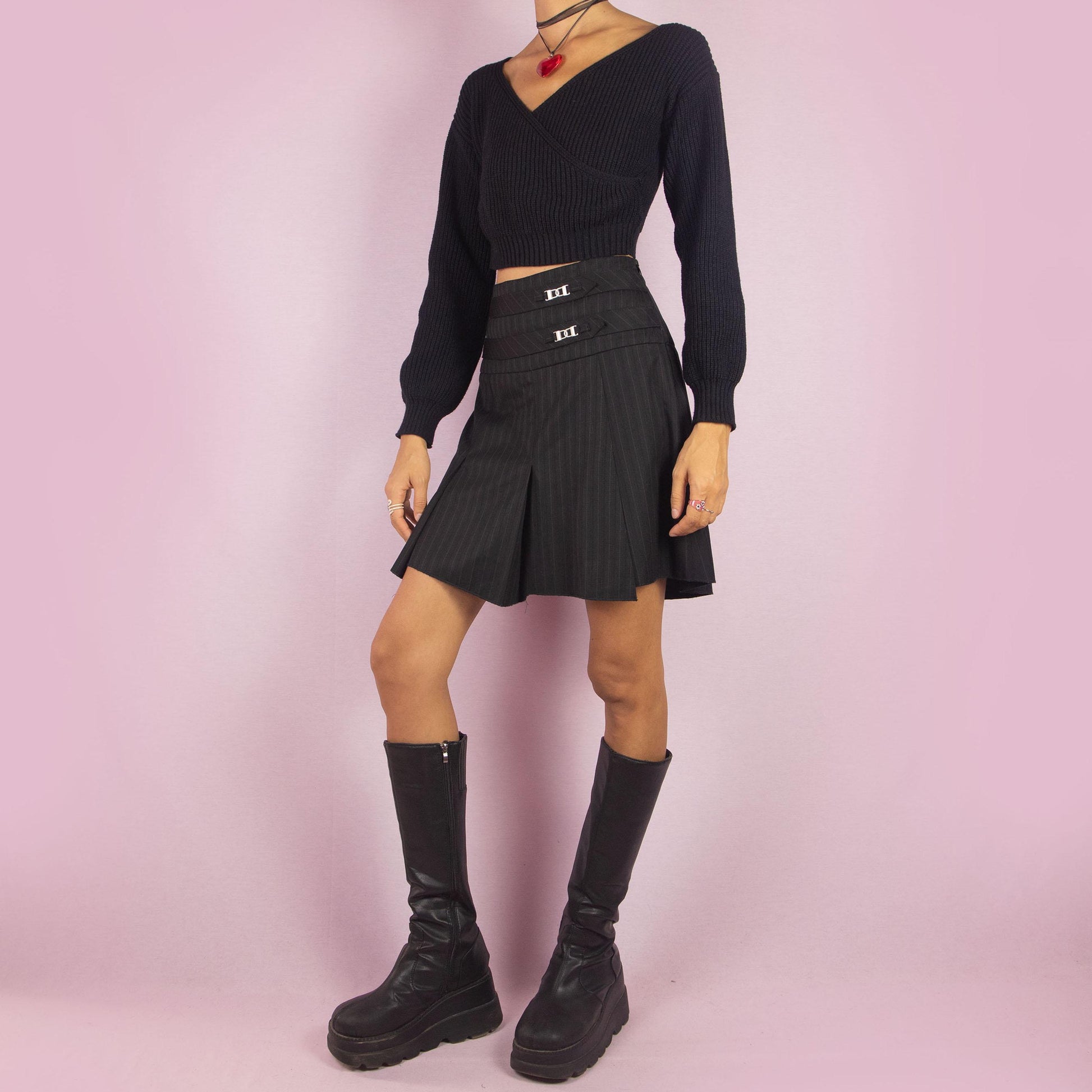 The Y2K Pinstripe Pleated Mini Skirt is a vintage 2000s piece featuring a classic pinstripe pattern with pleated detailing in black. Designed with a mid-rise fit, mini length, and side zipper closure, it’s perfect for office-to-evening transitions