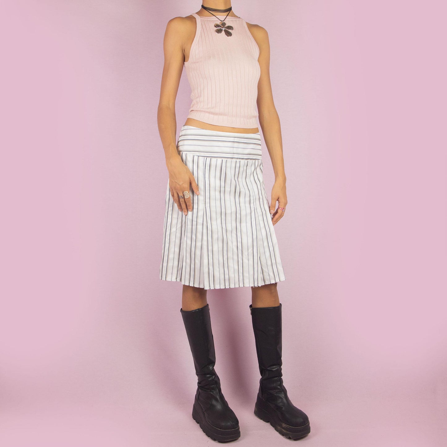 The Vintage 90s White Pinstripe Pleated Skirt features a classic pinstripe pattern with a flared silhouette, a mid-waist fit and a back zipper closure. Perfect for both office wear and casual outings.