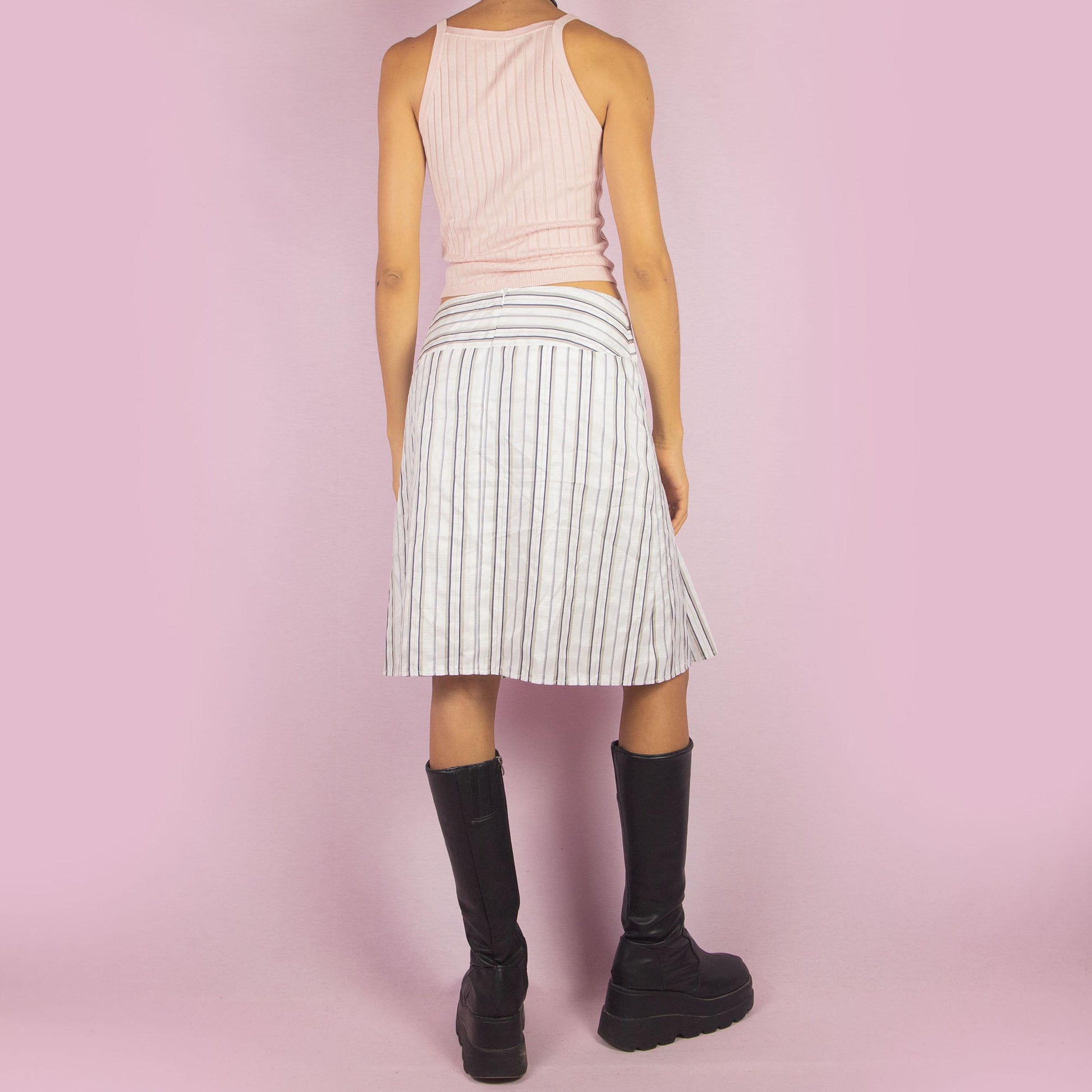 The Vintage 90s White Pinstripe Pleated Skirt features a classic pinstripe pattern with a flared silhouette, a mid-waist fit and a back zipper closure. Perfect for both office wear and casual outings.