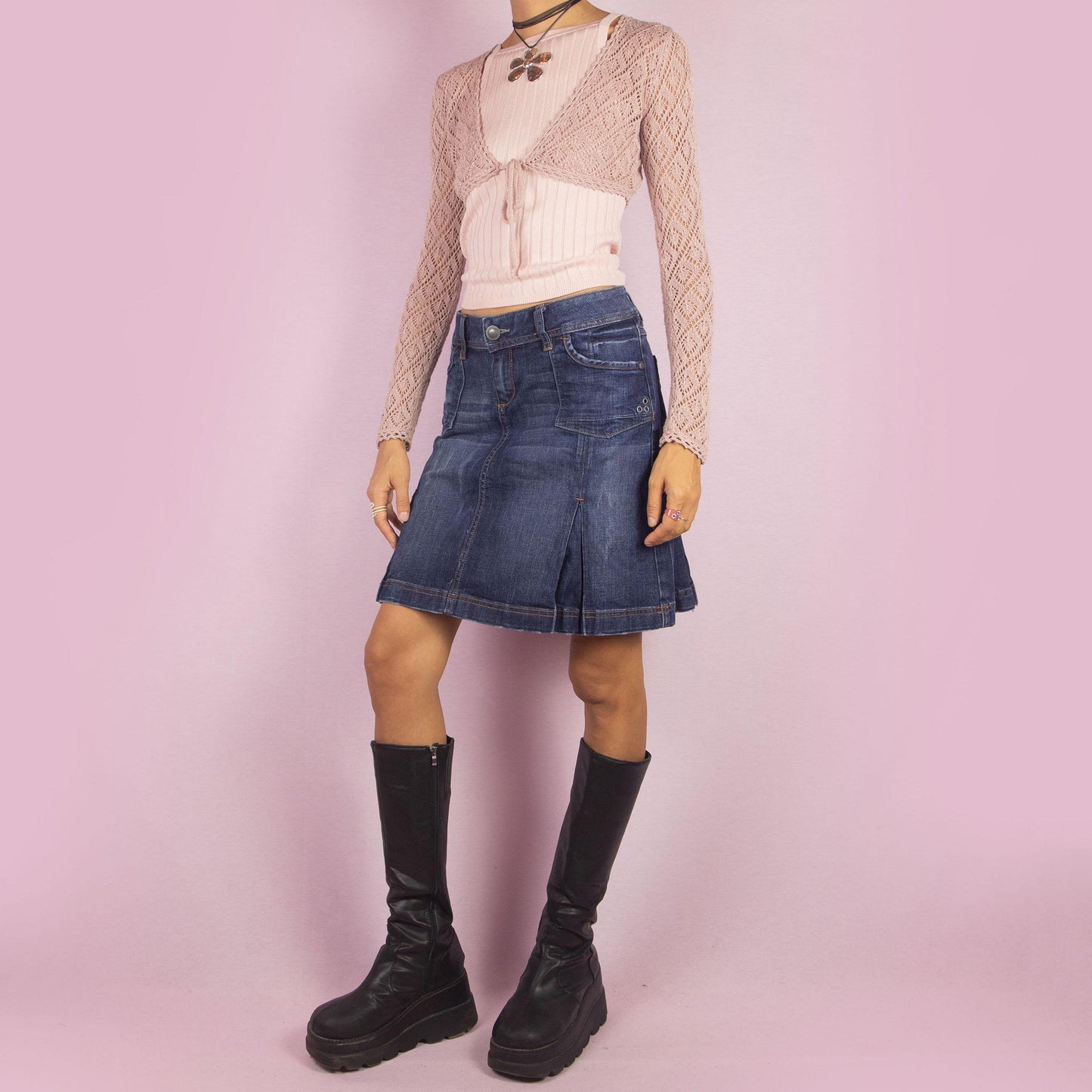 The Y2K Denim Pleated Skirt is a vintage 2000s piece featuring a structured A-line design with stitched pleats, pockets, a button-and-zipper front closure and stretchy fabric. Ideal for casual and chic everyday outfits.