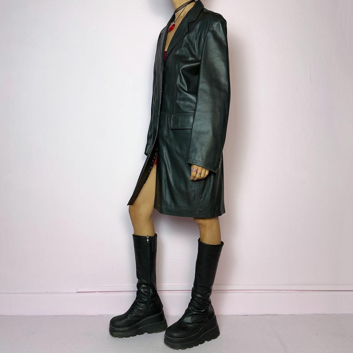 The Vintage 90s Black Leather Coat features a timeless design crafted from genuine black leather, with a button-front closure and a tailored silhouette. Complete with pockets, this versatile coat is ideal for both casual and formal occasions.