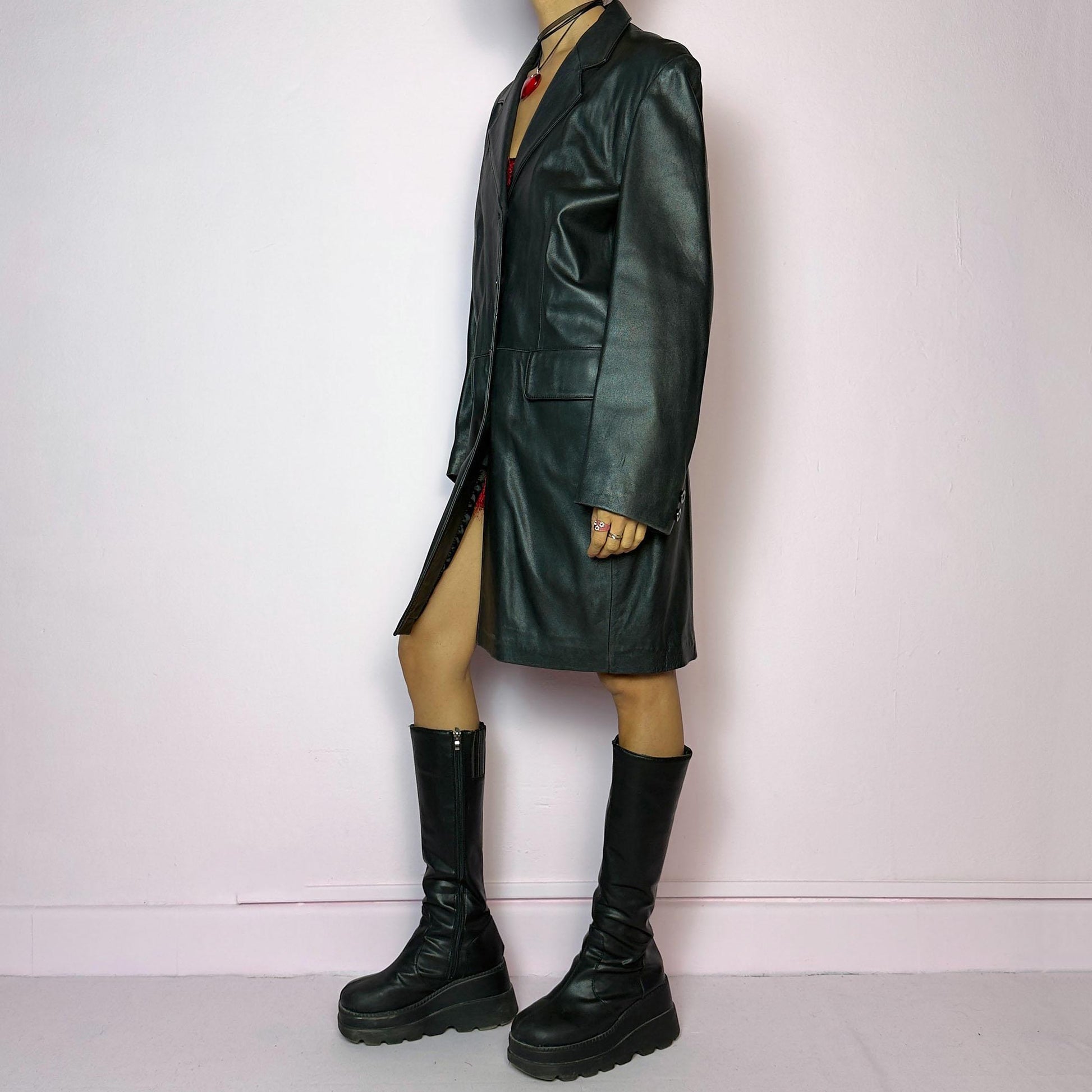 The Vintage 90s Black Leather Coat features a timeless design crafted from genuine black leather, with a button-front closure and a tailored silhouette. Complete with pockets, this versatile coat is ideal for both casual and formal occasions.