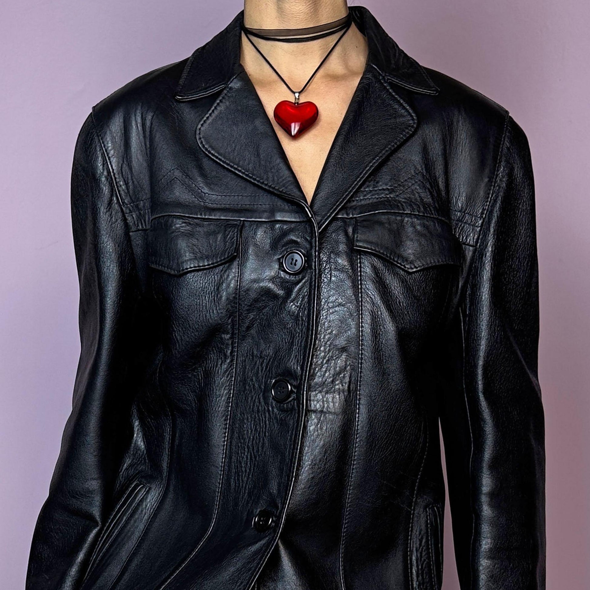 The Vintage 90s Black Leather Jacket features a sleek and structured design crafted from genuine black leather. With a button-front closure, pointed collar, and pockets, this jacket is a versatile staple for adding an edgy touch to casual