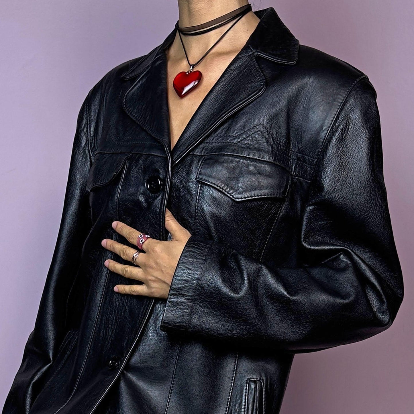 The Vintage 90s Black Leather Jacket features a sleek and structured design crafted from genuine black leather. With a button-front closure, pointed collar, and pockets, this jacket is a versatile staple for adding an edgy touch to casual