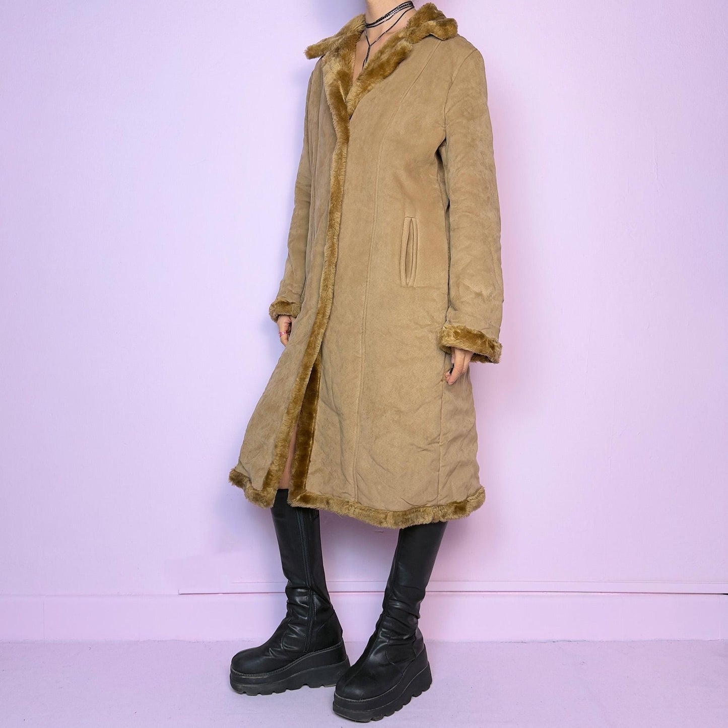 The Y2K Faux Suede Maxi Coat is a vintage 2000s cozy piece featuring a classic camel-tone faux suede exterior accented with plush faux fur trim along the collar, cuffs, and hem. This longline coat includes button-front closures and a tailored fit