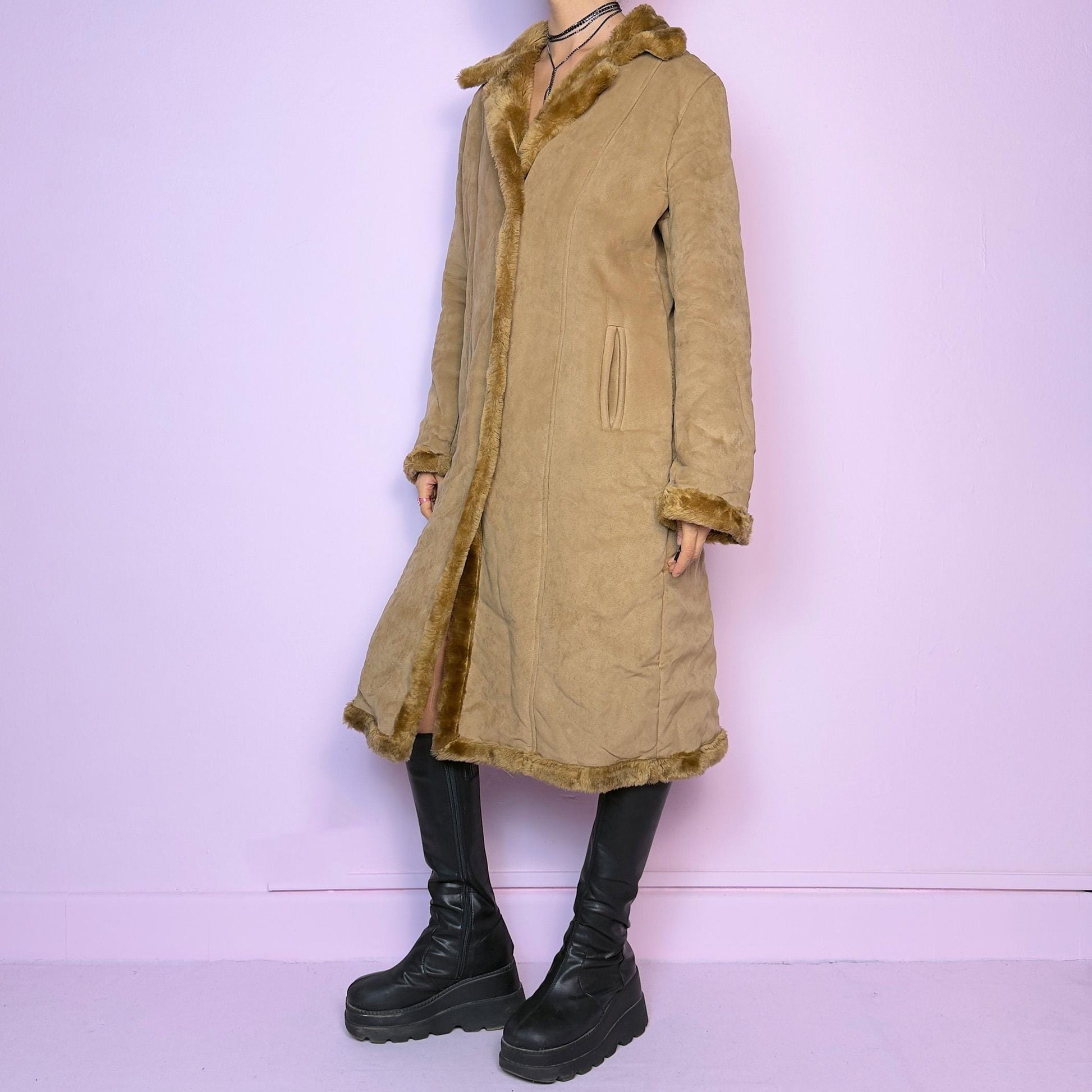 The Y2K Faux Suede Maxi Coat is a vintage 2000s cozy piece featuring a classic camel-tone faux suede exterior accented with plush faux fur trim along the collar, cuffs, and hem. This longline coat includes button-front closures and a tailored fit