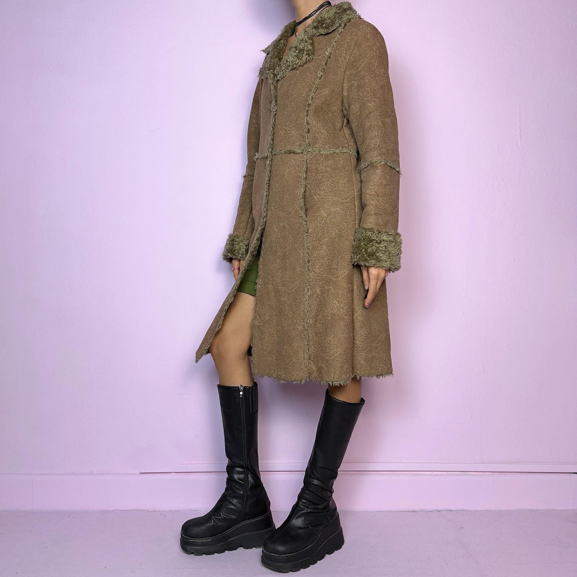 The Y2K Faux Fur Suede Long Coat is a vintage 2000s cozy piece featuring a soft brown faux suede exterior and faux shearling trim along the collar, cuffs, and seams. Its structured silhouette features button-front closure and pockets