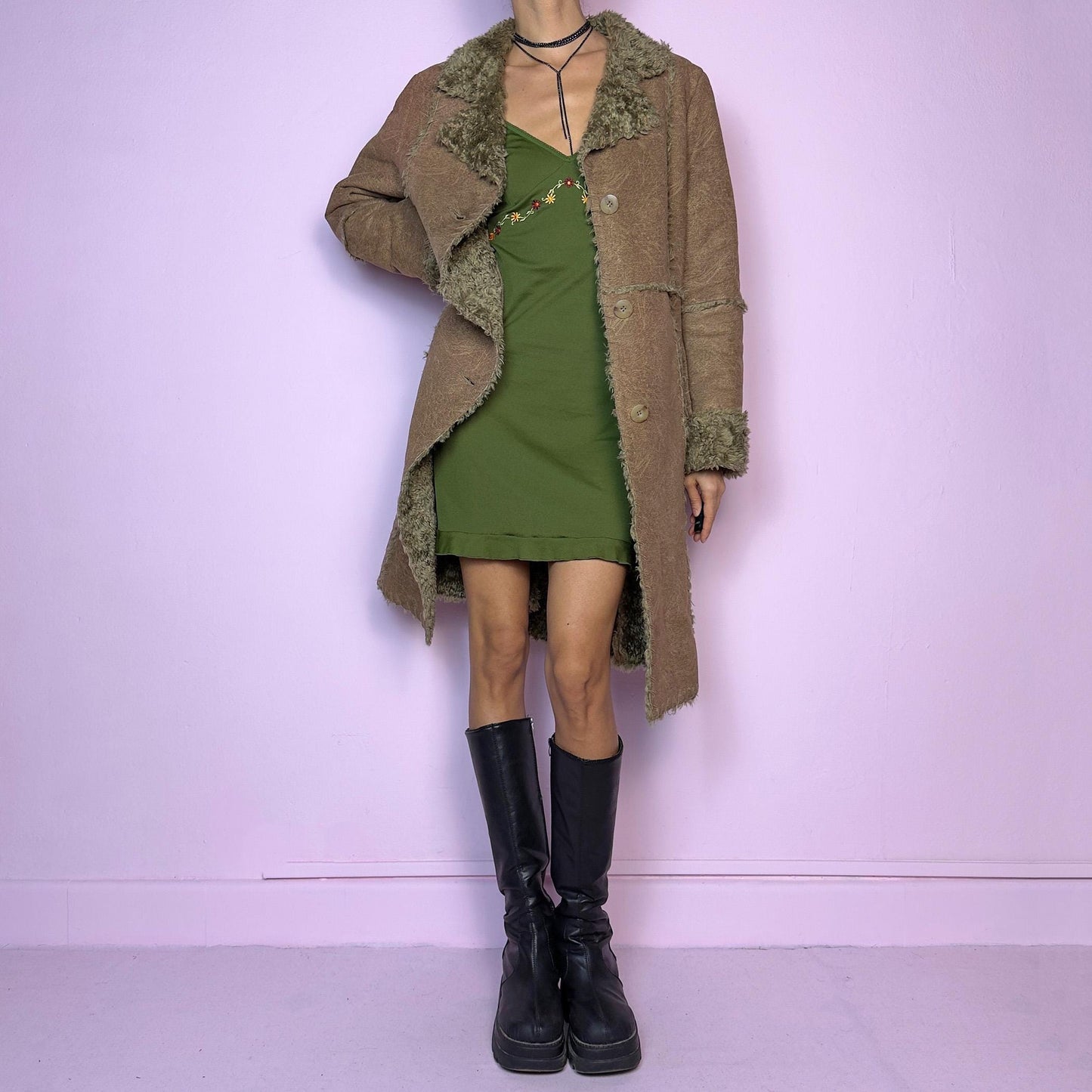 The Y2K Faux Fur Suede Long Coat is a vintage 2000s cozy piece featuring a soft brown faux suede exterior and faux shearling trim along the collar, cuffs, and seams. Its structured silhouette features button-front closure and pockets