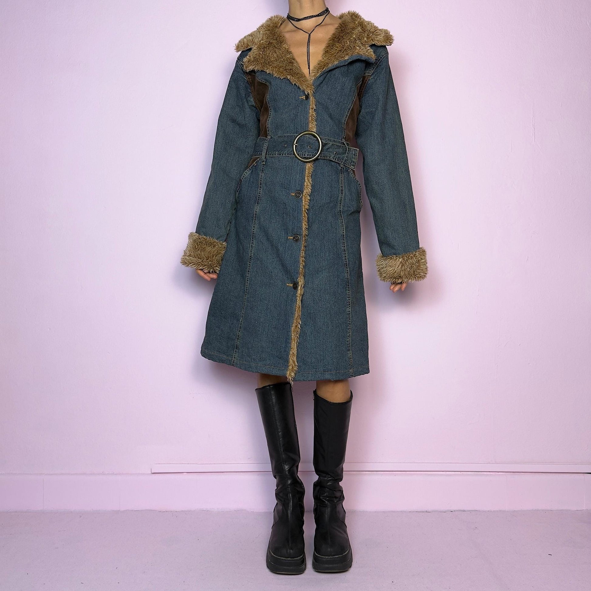 The Y2K Faux Fur Denim Coat is a vintage 2000s piece blending blue denim with cozy brown faux fur trim along the collar, front, cuffs, and hem. It also includes a matching belt with a circular buckle that creates a flattering silhouette