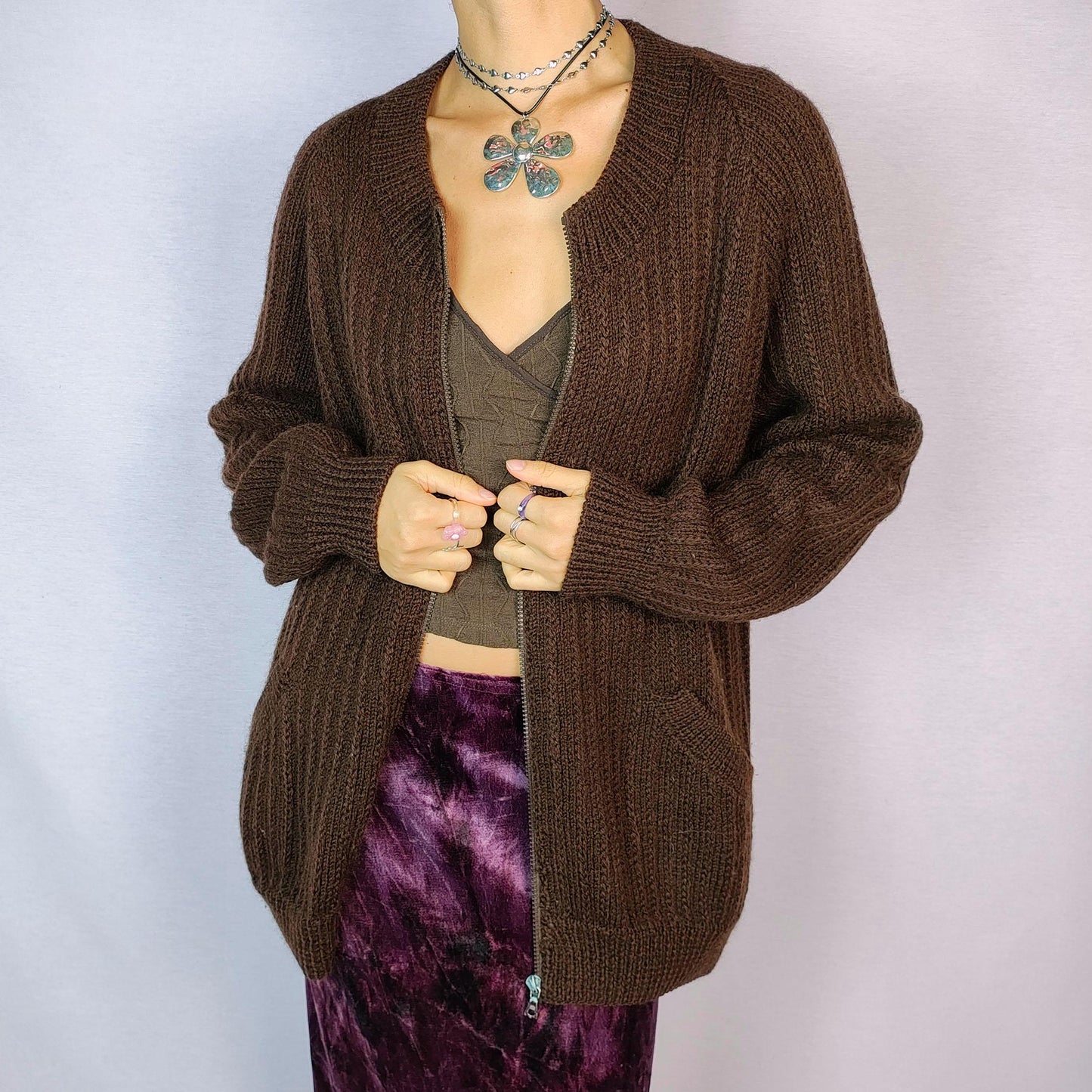 The Vintage 90s Brown Zip Cardigan features a relaxed fit with a ribbed knit design, full front zipper closure, and two pockets for a functional yet cozy style. Crafted in a dark warm brown tone, this versatile piece is perfect for layering