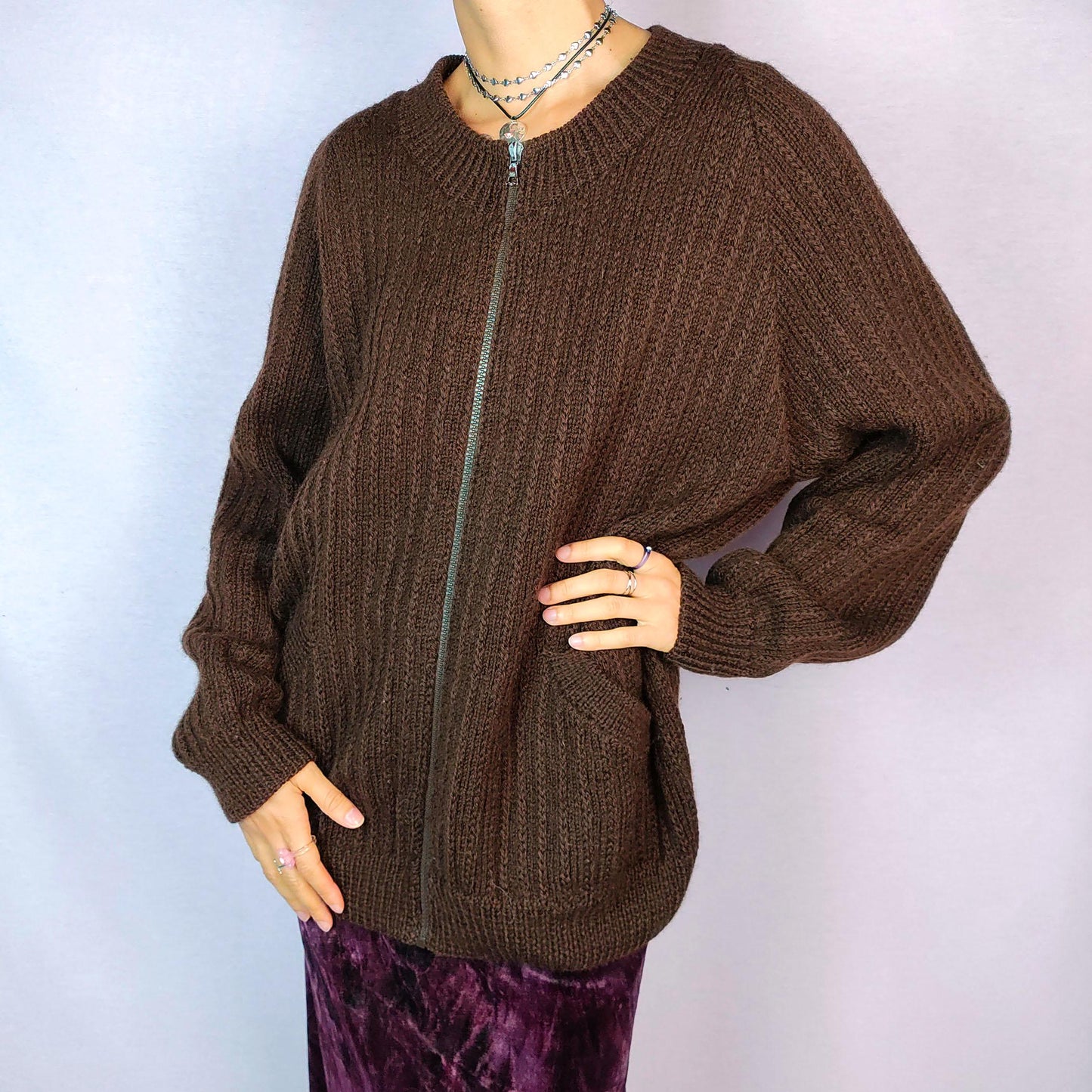 The Vintage 90s Brown Zip Cardigan features a relaxed fit with a ribbed knit design, full front zipper closure, and two pockets for a functional yet cozy style. Crafted in a dark warm brown tone, this versatile piece is perfect for layering